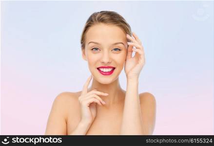 beauty, cosmetics, people and health concept - smiling young woman with pink lipstick on lips touching her face over rose quartz and serenity gradient background