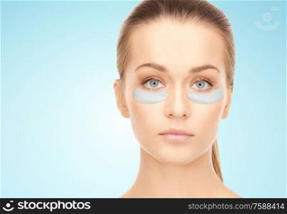 beauty, cosmetology and people concept - beautiful young woman face with hydrogel under-eye patches over blue background. beautiful young woman face with under-eye patches