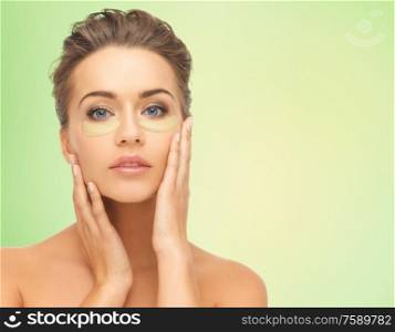 beauty, cosmetology and people concept - beautiful young woman face with hydrogel under-eye patches over lime green natural background. beautiful young woman face with under-eye patches