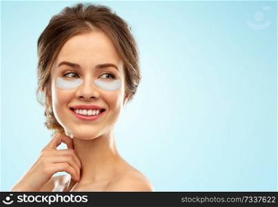 beauty, cosmetology and rejuvenation concept - beautiful young woman face with hydrogel under-eye patches over blue background. beautiful young woman face with under-eye patches