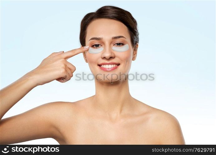 beauty, cosmetology and rejuvenation concept - beautiful young woman with hydrogel under-eye patches over blue background. beautiful young woman with under-eye patches