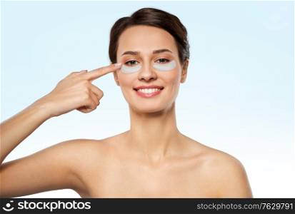 beauty, cosmetology and rejuvenation concept - beautiful young woman with hydrogel under-eye patches over blue background. beautiful young woman with under-eye patches