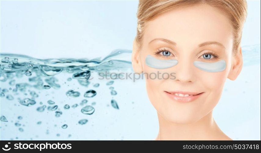 beauty, cosmetology, hydration, people and rejuvenation concept - close up of beautiful young woman face with hydrogel under-eye patches over blue background and water bubbles. close up of woman face with under-eye patches