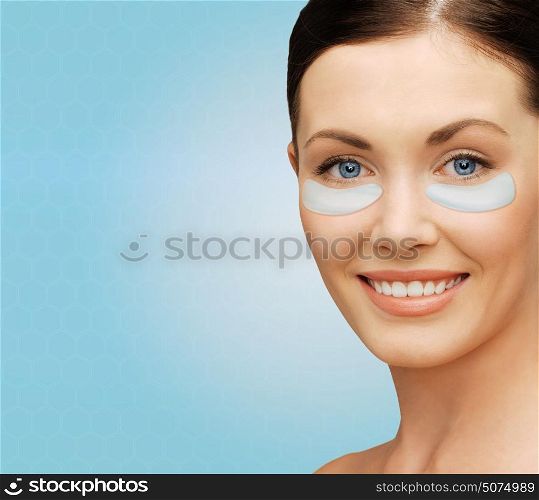 beauty, cosmetology, hydration, people and rejuvenation concept - close up of beautiful young woman face with hydrogel under-eye patches over blue background. close up of woman face with under-eye patches