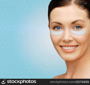 beauty, cosmetology, hydration, people and rejuvenation concept - close up of beautiful young woman face with hydrogel under-eye patches over blue background. close up of woman face with under-eye patches