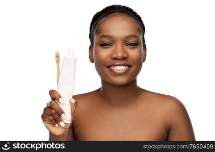 beauty, dental care and people concept - close up of of happy smiling young african american woman with wooden toothbrush and toothpaste over white background. african woman with toothbrush and toothpaste