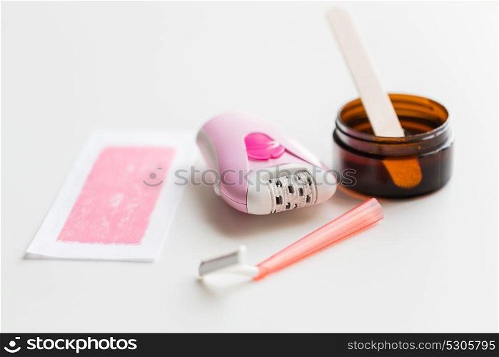 beauty, depilation and hair removal concept - epilator, safety razor, wax with spatula and patch on white background. safety razor, epilator, hair removal wax and patch