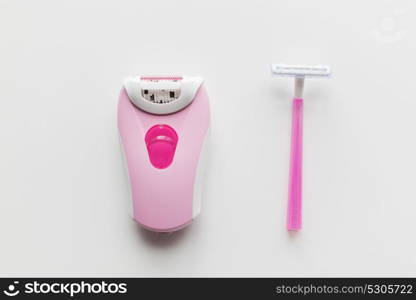 beauty, depilation and hair removal concept - safety razor and epilator on white background. safety razor and epilator