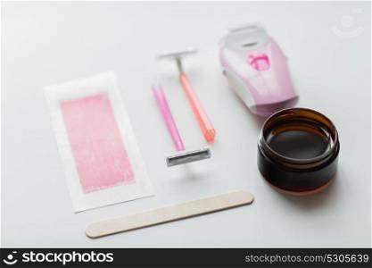beauty, depilation and hair removal concept - safety razor, epilator, wax and patch on white background. safety razor, epilator, hair removal wax and patch