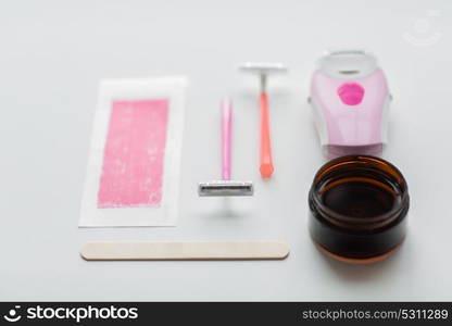 beauty, depilation and hair removal concept - safety razor, epilator, wax and patch on white background. safety razor, epilator, hair removal wax and patch