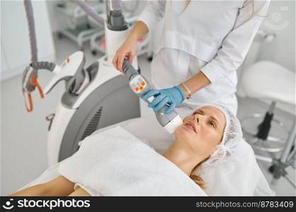 Beauty doctor doing face apparatus massage for woman client. Aesthetics facial therapy concept. Doctor cosmetologist doing face apparatus massage
