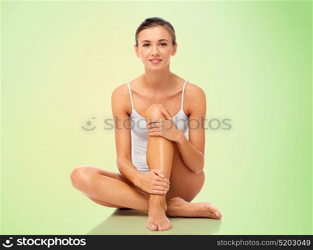beauty, epilation, people and bodycare concept - beautiful woman touching her smooth bare legs over green background. beautiful woman touching her smooth bare legs