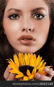 beauty face shot of a young girl holding a sunflower in her hands