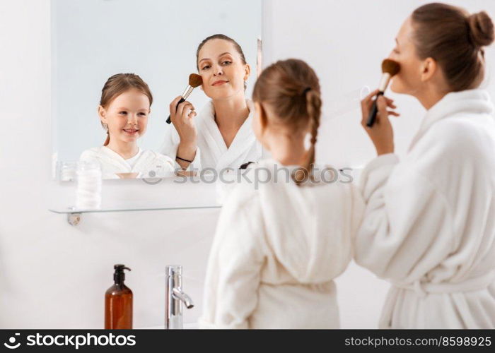 beauty, family and people concept - happy smiling mother and little daughter applying make up in bathroom. mother and daughter applying make up in bathroom