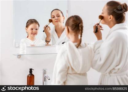 beauty, family and people concept - happy smiling mother and little daughter applying make up in bathroom. mother and daughter applying make up in bathroom