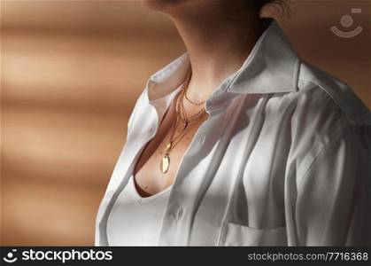 beauty, fashion and jewelry trends concept - close up of woman in white shirt wearing golden multi layer necklace with coin medallions. close up of woman with multi layer gold chains