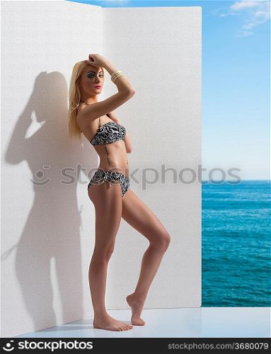 beauty fashion girl wearing sexy bikini, some bracelets and posing near white wall. Blue sky and sea on the background
