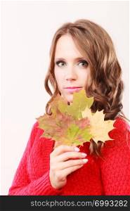 Beauty female autumnal model. Attractive girl long hair wearing warm red sweater with maple leaves in hand