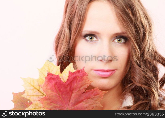 Beauty female autumnal model. Lovely girl long hair with dry fall maple leaves in hand studio shot bright pink background