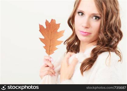 Beauty female autumnal model. Pretty girl long hair with oak leaf in hand