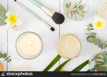 Beauty flat lay background with facial cosmetic products, succulents and flowers on white wooden background. Beauty background with facial cosmetic products