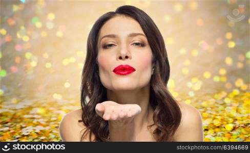 beauty, gesture and valentines day concept - beautiful woman with red lipstick blowing air kisses over background with glitter. beautiful woman with red lipstick blowing air kiss