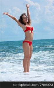 beauty girl stands in sea surf with rised hands