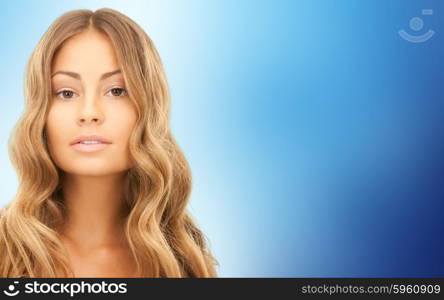 beauty, hair care, people and hairstyle concept - beautiful young woman face with long wavy hair over blue background