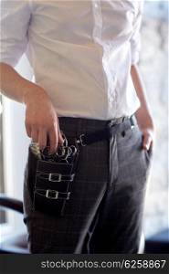 beauty, hairstyle and people concept - close up of male stylist with tool case on belt at salon