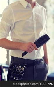 beauty, hairstyle and people concept - close up of male stylist with brush at salon