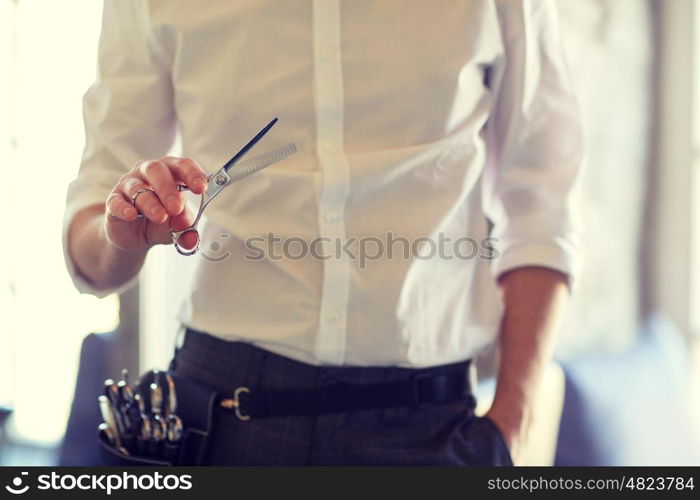 beauty, hairstyle and people concept -close up of male stylist with scissors at salon
