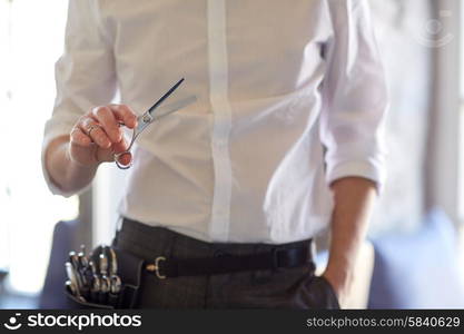 beauty, hairstyle and people concept -close up of male stylist with scissors at salon