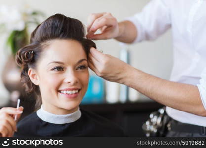 beauty, hairstyle and people concept - happy young woman with hairdresser making hairdo at salon