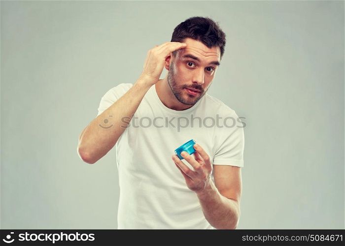 beauty, hairstyle, haircare and people concept - happy young man styling his hair with wax or gel over gray background. happy young man styling his hair with wax or gel. happy young man styling his hair with wax or gel