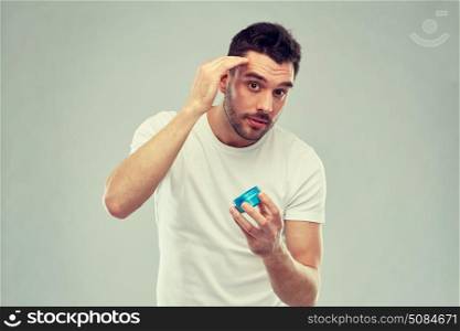 beauty, hairstyle, haircare and people concept - happy young man styling his hair with wax or gel over gray background. happy young man styling his hair with wax or gel. happy young man styling his hair with wax or gel