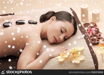 beauty, health, holidays, people and spa concept - beautiful woman in spa salon getting hot stones massage