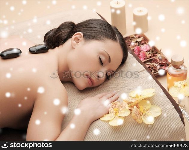 beauty, health, holidays, people and spa concept - beautiful woman in spa salon getting hot stones massage