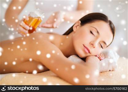 beauty, health, holidays, people and spa concept - beautiful young woman in spa salon getting oil massage