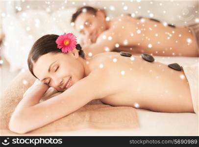 beauty, health, holidays, people and spa concept - happy couple with closed eyes getting hot stone massage in spa salon