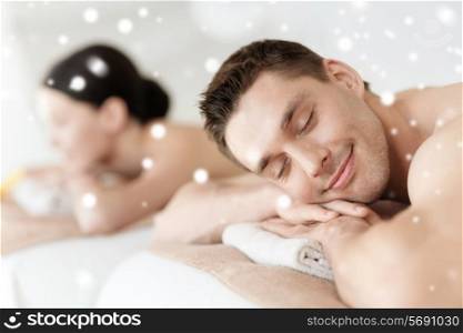 beauty, health, holidays, people and spa concept - happy couple with closed eyes lying in spa salon