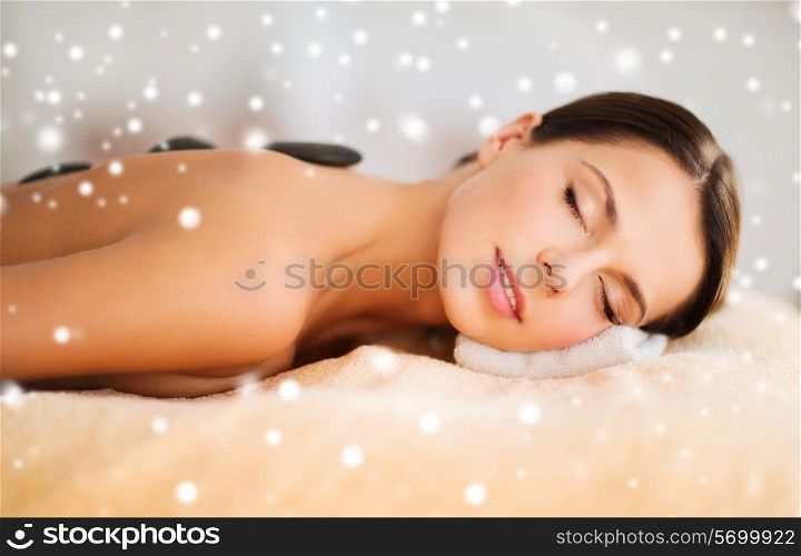 beauty, health, people and spa concept - beautiful woman in spa salon getting hot stones massage