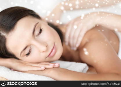 beauty, health, people and spa concept - beautiful young woman in spa salon lying on the massage desk