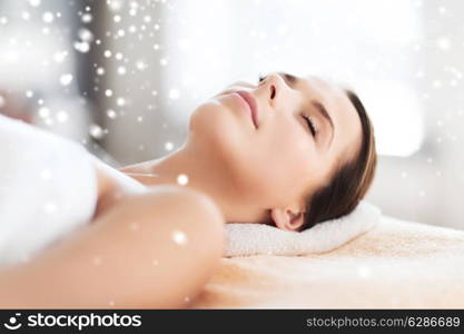 beauty, health, people and spa concept - beautiful young woman in spa salon lying on the massage desk