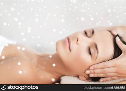 beauty, health, people and spa concept - beautiful young woman in spa salon lying on the massage desk