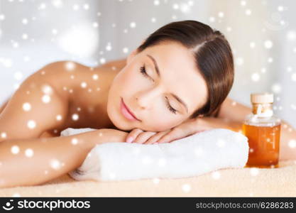 beauty, health, people and spa concept - beautiful young woman with body oil in spa