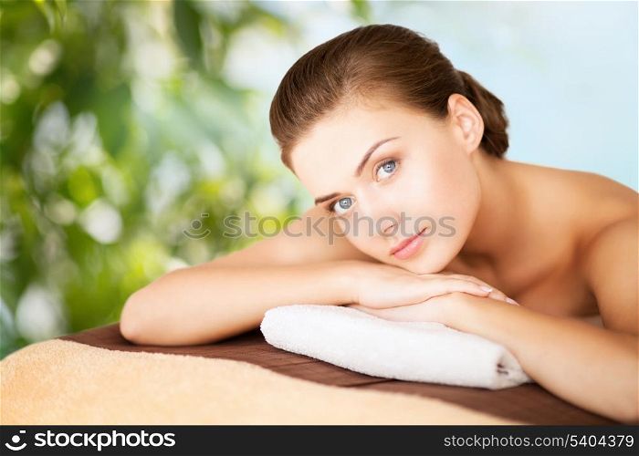 beauty, holidays and spa concept - woman in spa salon lying on the massage desk