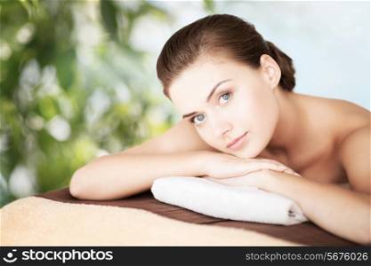 beauty, holidays and spa concept - woman in spa salon lying on the massage desk