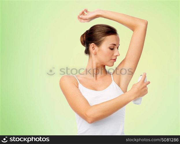 beauty, hygiene and people concept - beautiful young woman applying antiperspirant or spray deodorant over green background. woman with antiperspirant deodorant over white