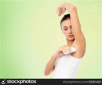 beauty, hygiene and people concept - beautiful young woman applying antiperspirant or stick deodorant over green background. woman with antiperspirant deodorant over white