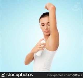 beauty, hygiene and people concept - beautiful young woman applying antiperspirant or spray deodorant over blue background. woman with antiperspirant deodorant over white